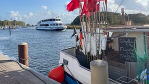 Un bote atracado en una marina, con un cartel que indica actividades de pesca y precios.