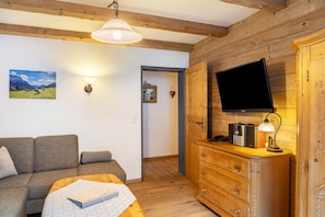 Una habitación acogedora con sofá, un mueble de madera con televisor de pantalla plana y una lámpara.
