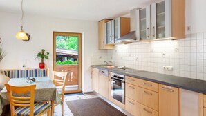 Une cuisine avec des meubles en bois, un four encastré et un coin repas comprenant une table et des chaises.