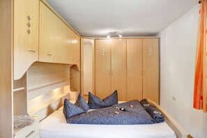 Une chambre à coucher comprenant un lit, des oreillers, une armoire et un petit coin salon.