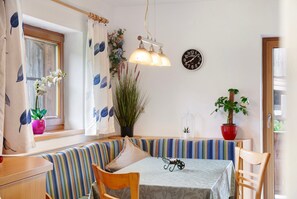 Une pièce chaleureuse avec un banc à rayures, une table avec une horloge et des plantes en pot.