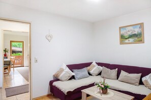 Un salon avec un canapé violet, une table basse en bois et un tableau accroché au mur.
