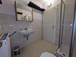 Ein Badezimmer mit Waschbecken, Spiegel, Toilette und Dusche.
