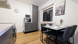 Une cuisine compacte équipée d’un four à micro-ondes, d’une machine à café et d’un coin repas avec une table dressée pour deux personnes.
