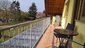 Ein Balkon mit Glasgeländer, einem Tisch und Stühlen sowie Blick auf die Umgebung.