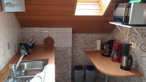 Eine kleine Küche mit Dachfenster, einer Mikrowelle, einer Kaffeemaschine und zwei Mülleimern.