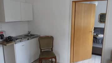 Een koelkast, een kookplaat, een waterkoker, kookgerei, borden en bestek