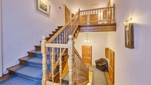 Un escalier en bois avec une rampe, des marches recouvertes de moquette et une chaise dans l’espace de repos situé à mi-parcours.