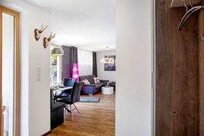 Uma sala de estar moderna com área de jantar, piso de madeira e uma grande janela com cortinas.