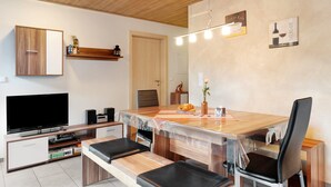 Una cocina moderna con encimera de madera, horno empotrado y comedor con mesa y sillas.