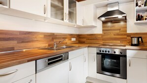 Una cocina moderna con armarios blancos, encimera de madera, horno de acero inoxidable y campana extractora integrada.