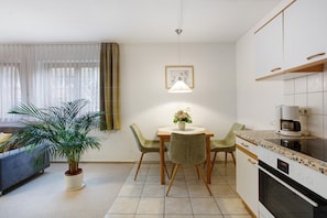 Una cocina moderna con una mesa de comedor, sillas, una planta en maceta y una cafetera.