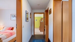 A hallway with a bed, wooden doors, and a blue rug.