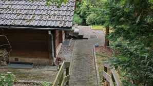 A pathway leading to a building with a tiled roof, surrounded by greenery.