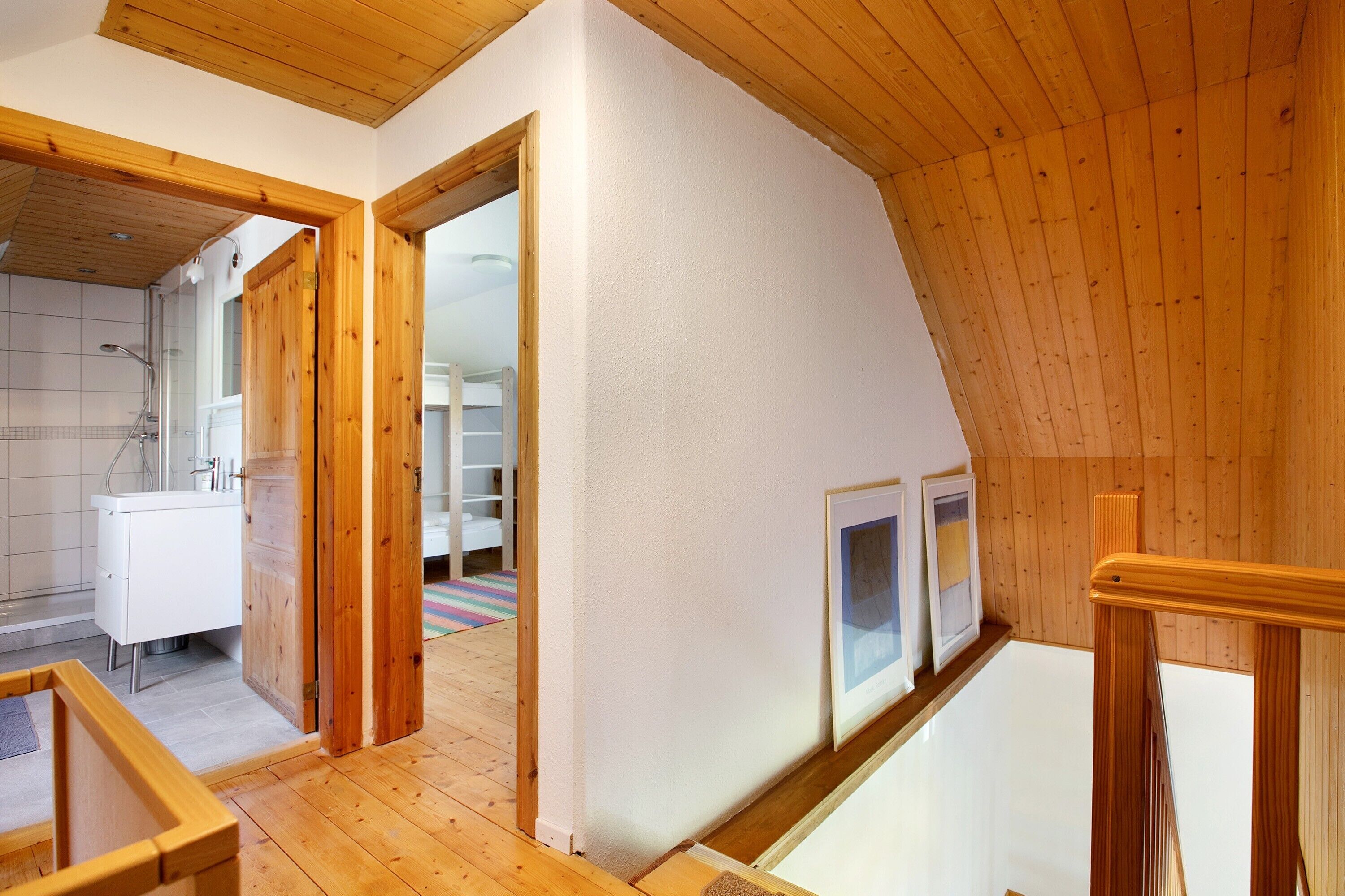 Una stanza in stile loft con travi in legno, parete bianca e pavimento in legno.