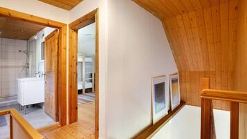 Una stanza in stile loft con travi in legno, parete bianca e pavimento in legno.