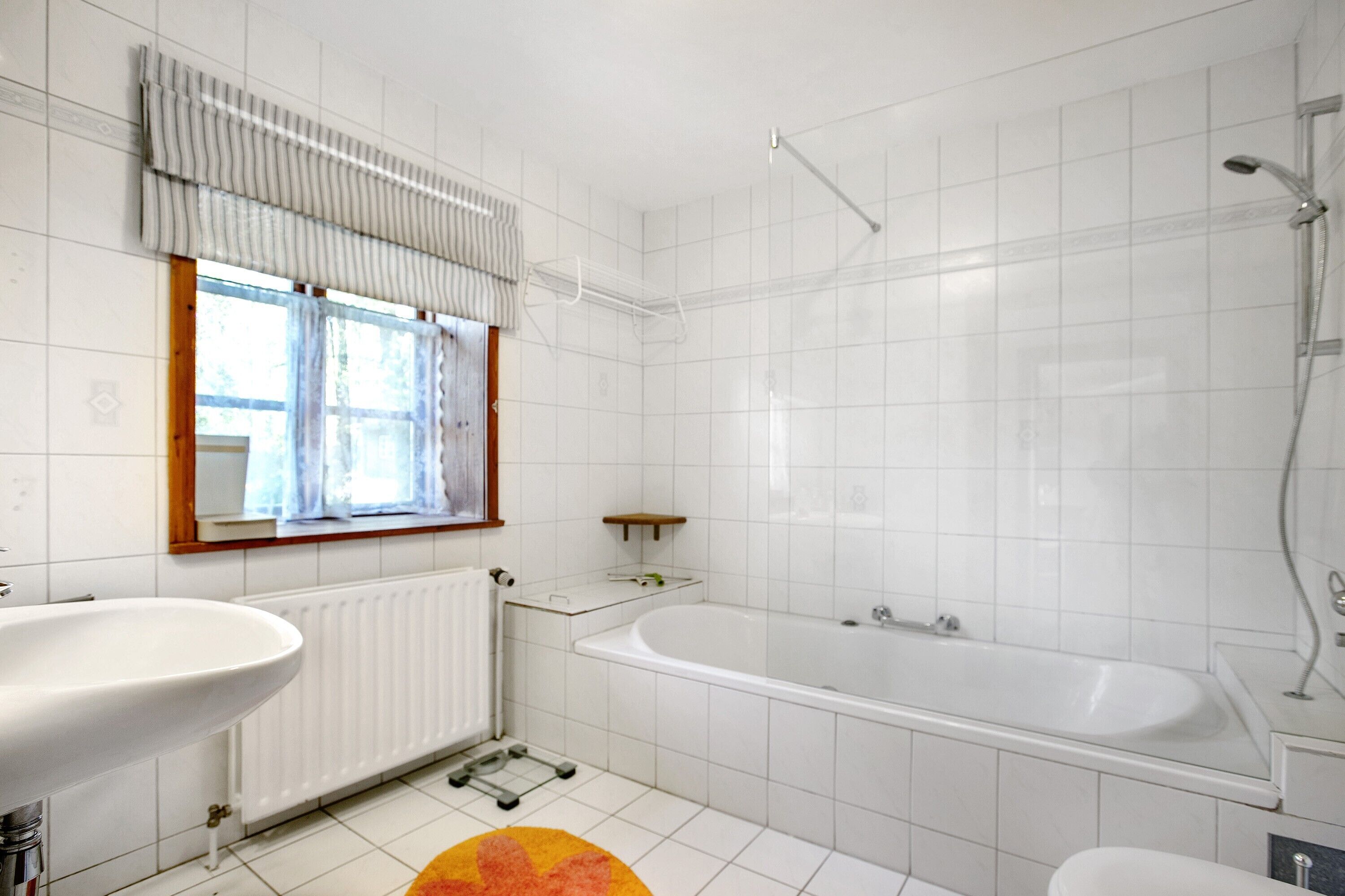 Un baño con lavamanos, bañera y ventana.