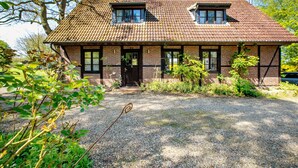 A two-story house with a tiled roof, a front porch, and a gravel driveway. - Holiday home "Rosen" with terrace and garden in an idyllic location - relax and unwind! (Gelting)