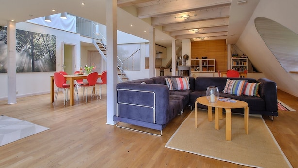 Spazioso loft con zona pranzo, divano e scala che conduce a un livello superiore.