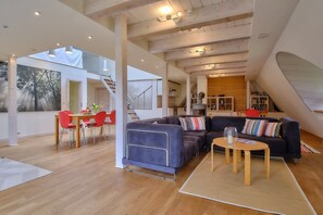 Un loft spacieux comprenant un coin repas, un canapé et un escalier menant à un niveau supérieur.