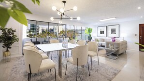 A modern dining area with a glass table, white chairs, and a city view. - Seaview balcony King Pacific Ocean Larcomar (Miraflores)