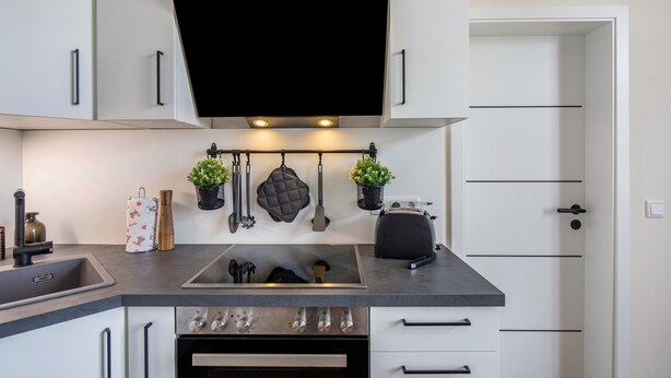A modern kitchen with a flat-screen TV, stainless steel appliances, and a built-in oven. - Apartment 'Residenz Unter Der Birke - Esche' with Mountain View, Shared Terrace and Wi-Fi (Eisenach)