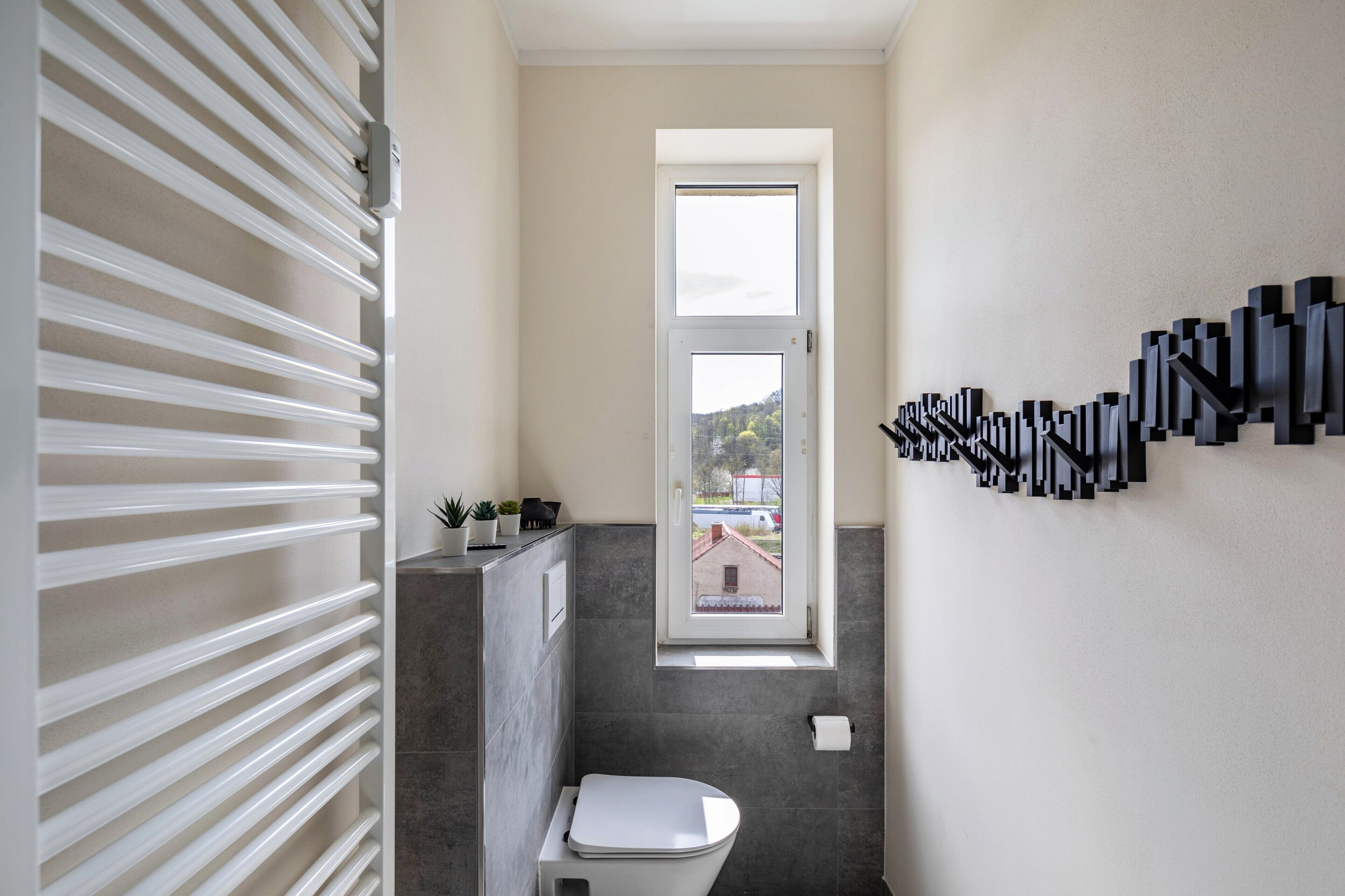 Ein modernes Badezimmer mit Toilette, Fenster und einer Wandleuchte.