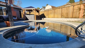 Piscina com deck de madeira e área coberta.