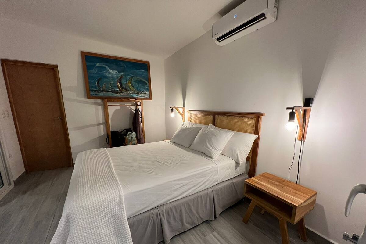 A neatly arranged bedroom with a bed, bedside table, and a painting on the wall.