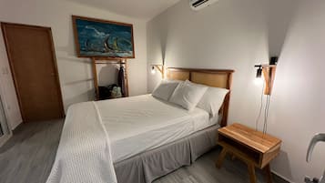 Une chambre à coucher bien rangée, avec un lit, une table de chevet et un tableau accroché au mur.
