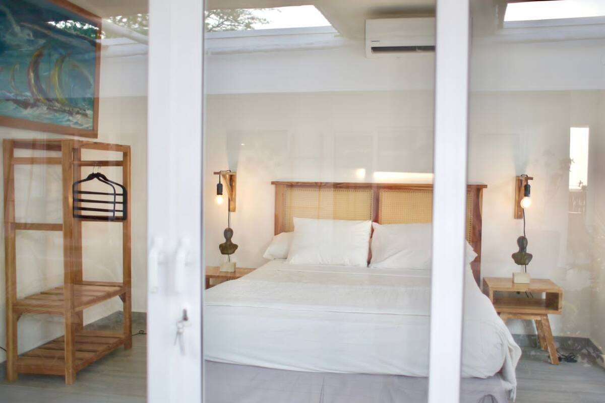 A bedroom with a bed, two bedside tables, and a wooden chair.
