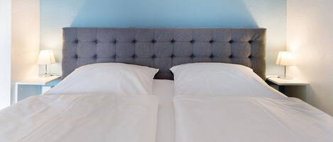 A bed with a tufted headboard, white bedding, and two bedside lamps on nightstands.