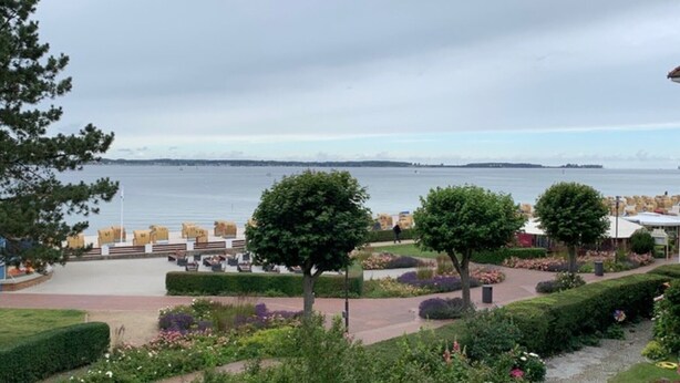 Et hotel ved vandet med have, udendørs siddepladser og udsigt over vandet.