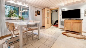 A modern interior with a dining area, a TV, and a wooden cabinet.