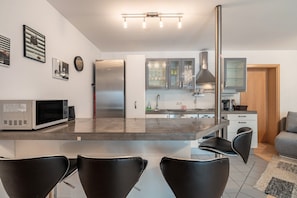 Una cucina moderna con isola centrale, elettrodomestici in acciaio inossidabile e sgabelli da bar neri.
