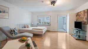 Ein modernes Schlafzimmer mit Bett, Nachttisch und TV-Schrank.