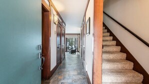 A hallway with a stone floor, wooden doors, and a carpeted staircase. - Central Tahoe Retreat | Lake Views + Walk to Shore (Tahoe City)