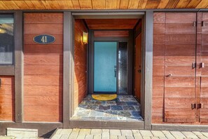Een modern gebouw met een stenen entree, een blauwe deur en een houten gevel.