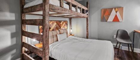 A bunk bed with a wooden headboard, a bedside table with a lamp, and a chair.