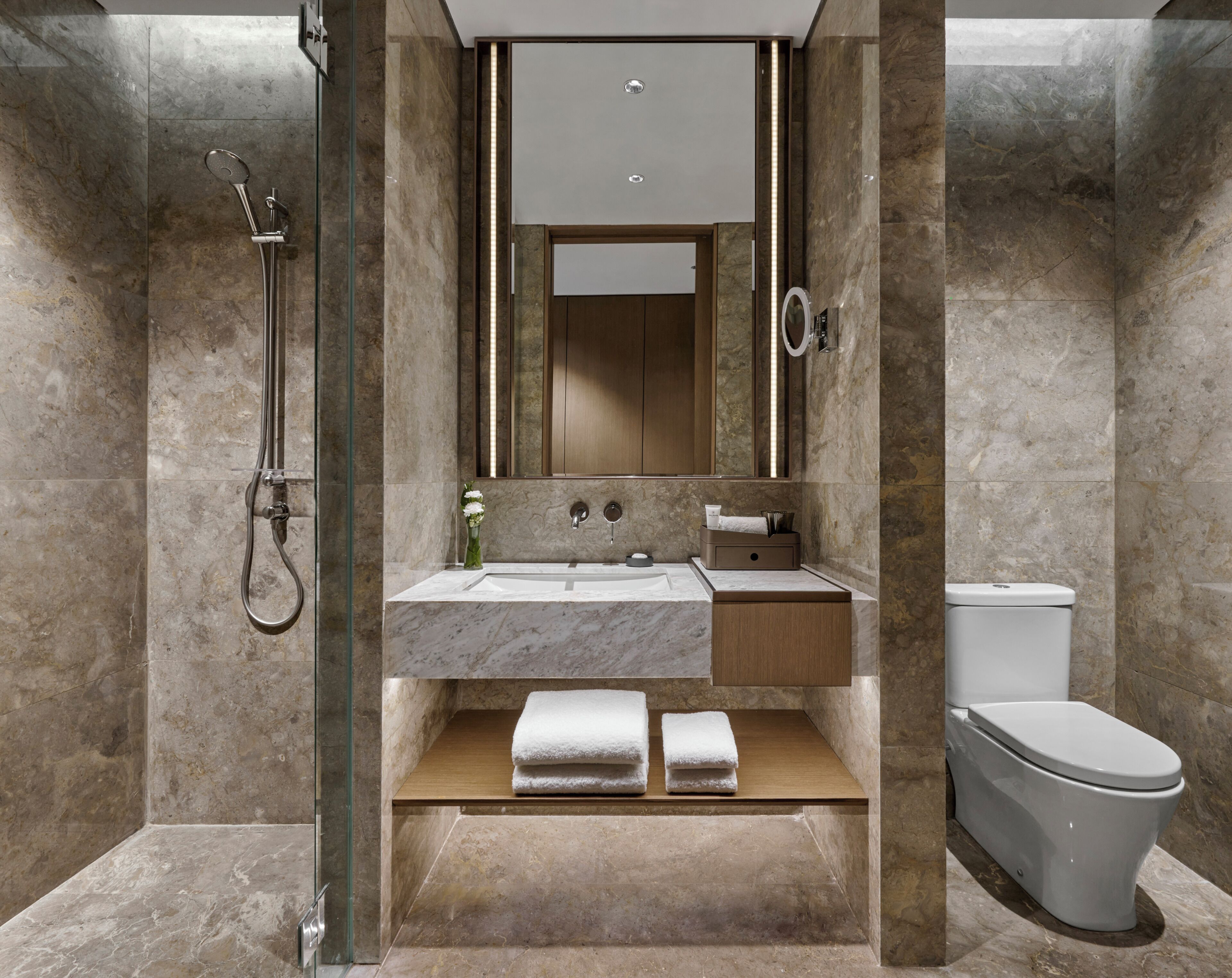 Une salle de bain moderne avec une douche à parois de verre, un lavabo en marbre et des toilettes.