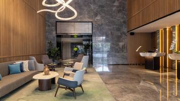 Un vestíbulo moderno con un sofá, sillones, una mesa de centro y un mostrador de recepción.