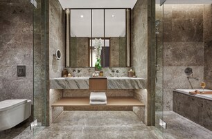 Un baño moderno con ducha de vidrio, tocador de mármol y un espejo grande.