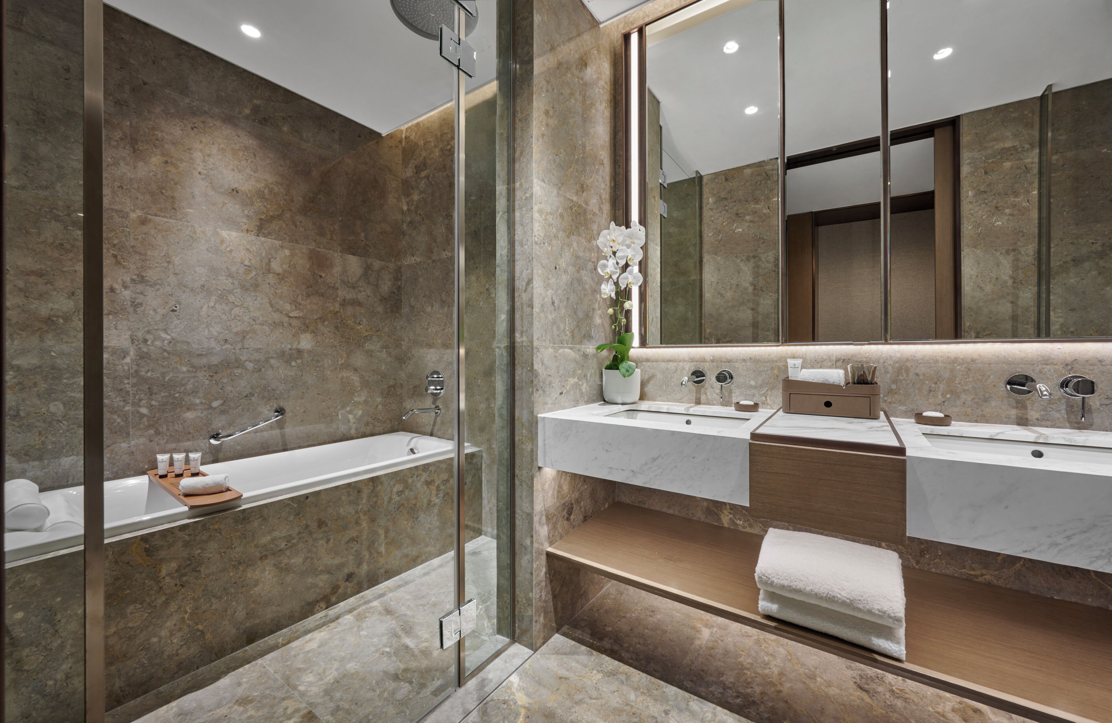 A modern bathroom with a glass-enclosed shower, a large mirror, and two sinks with wooden countertops.