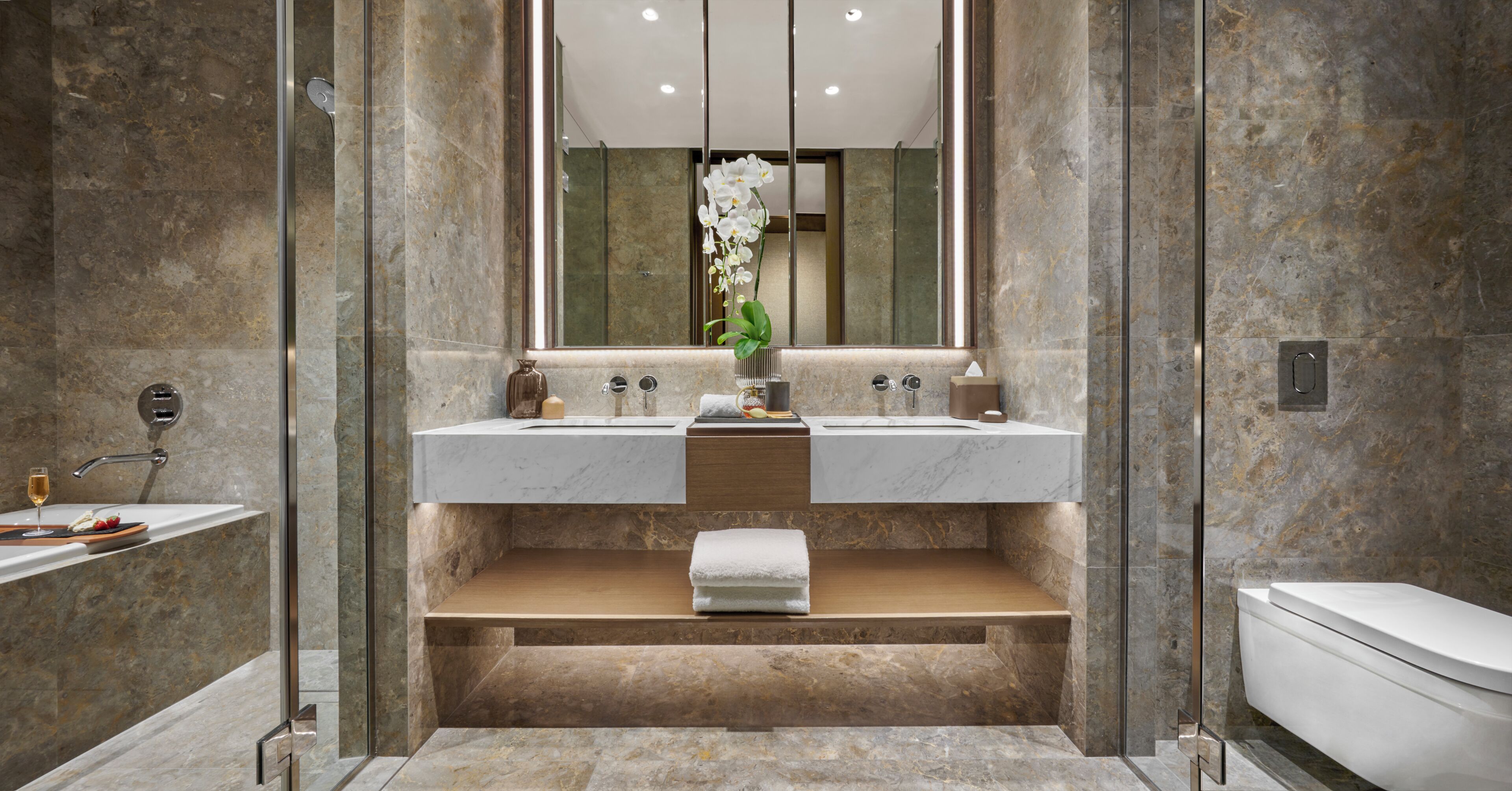 A modern bathroom with a double sink, a mirror, and a toilet.
