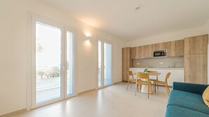 Un appartement moderne doté d'une cuisine, d'un coin repas et d'une grande porte-fenêtre coulissante donnant sur un balcon.