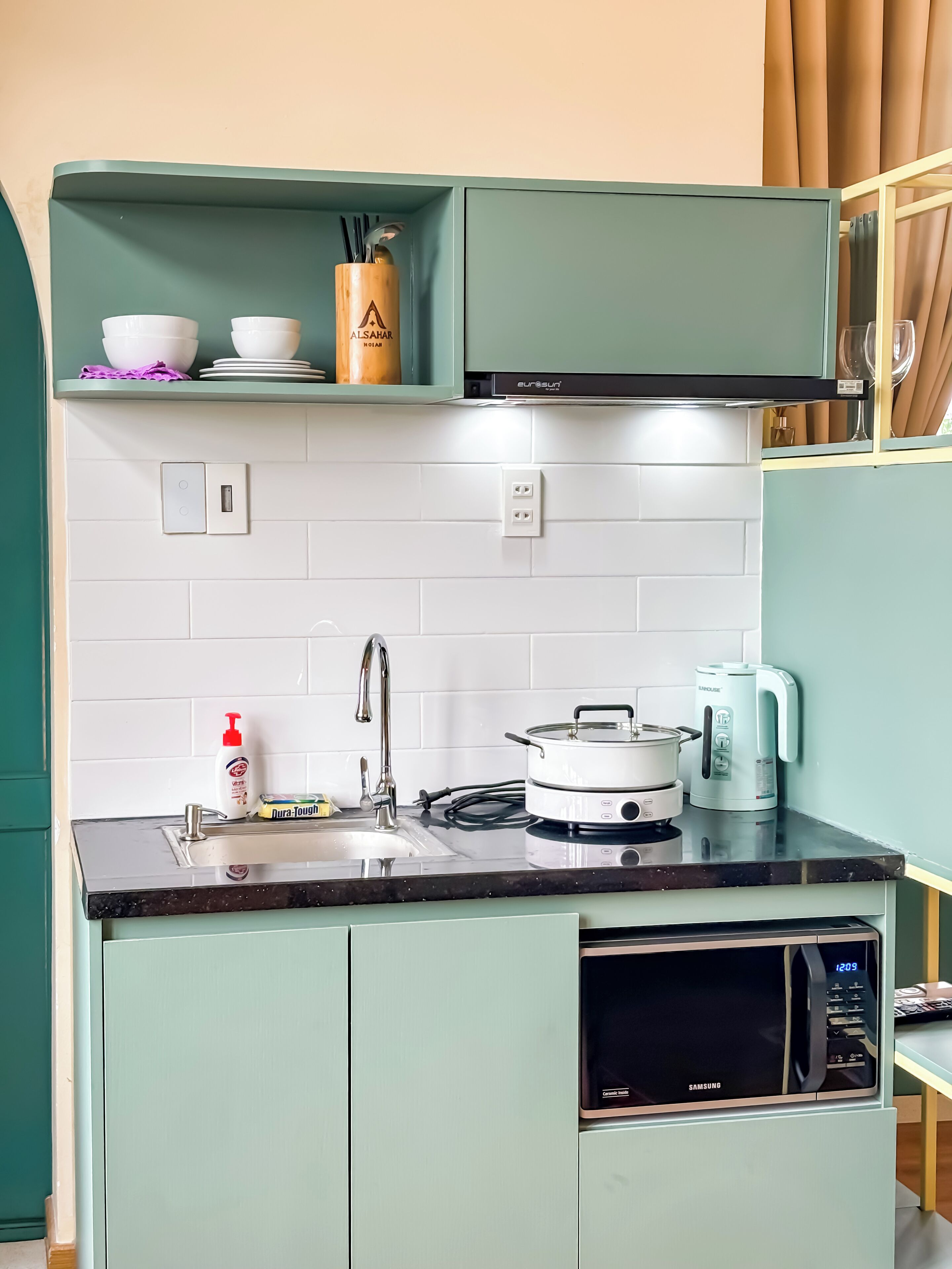 Une cuisine compacte équipée d’un four à micro-ondes, d’une bouilloire et d’une cuisinière.