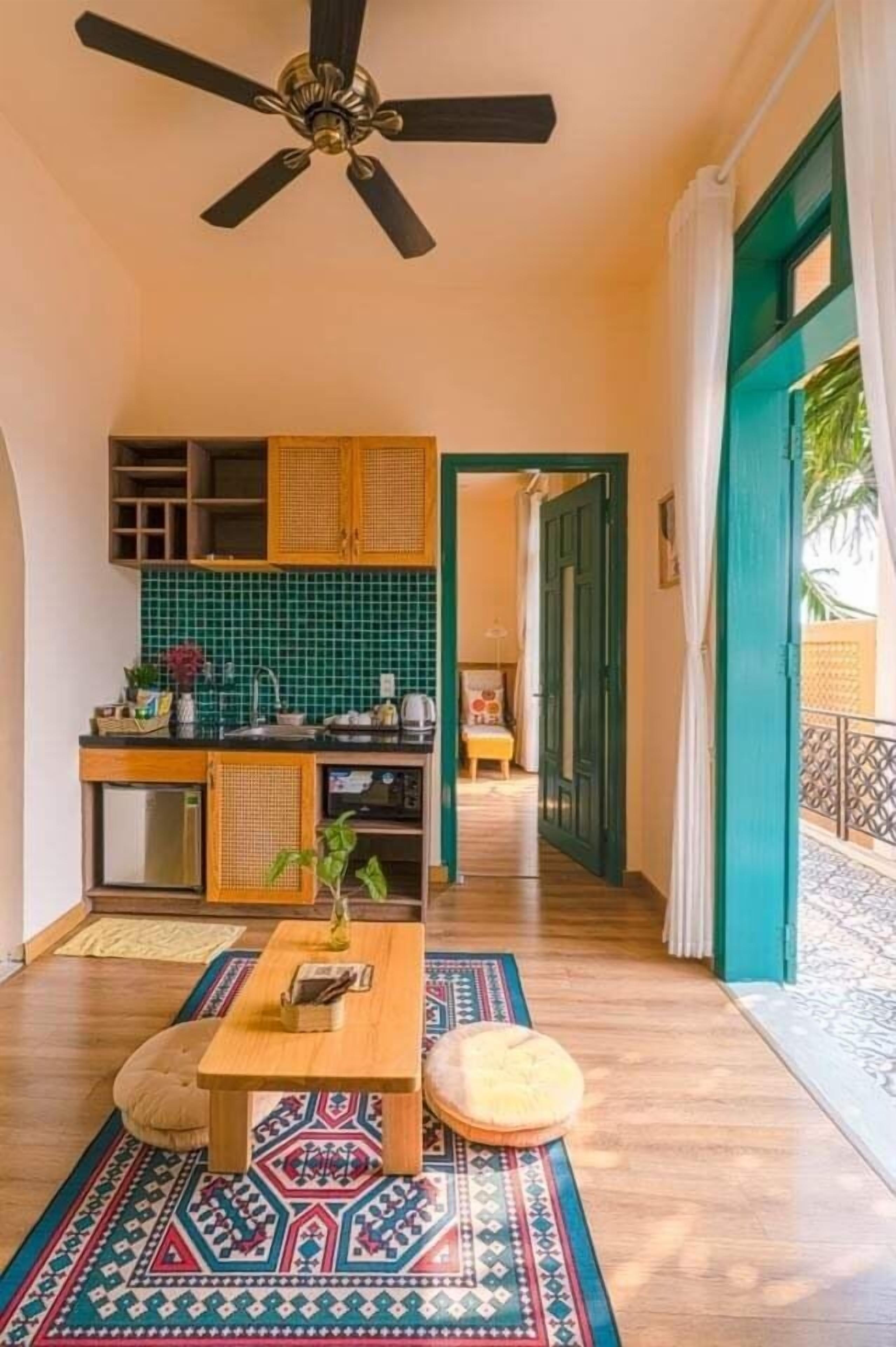 A modern kitchen with a green backsplash, wooden cabinets, and a ceiling fan.