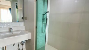 A modern bathroom with a glass shower enclosure, a white sink, and a mirror. - Seven Seas Condo Resort by PSR (Pattaya)