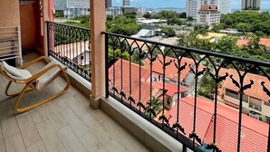 A balcony with a view of a cityscape, including tall buildings and a body of water. - Seven Seas Condo Resort by PSR (Pattaya)