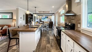 A modern kitchen with a central island, built-in appliances, and pendant lighting. - KY Lakeshore Retreat -Waterfront Views, Dock, Deck, Large Parking -NEW 2024 (New Concord)